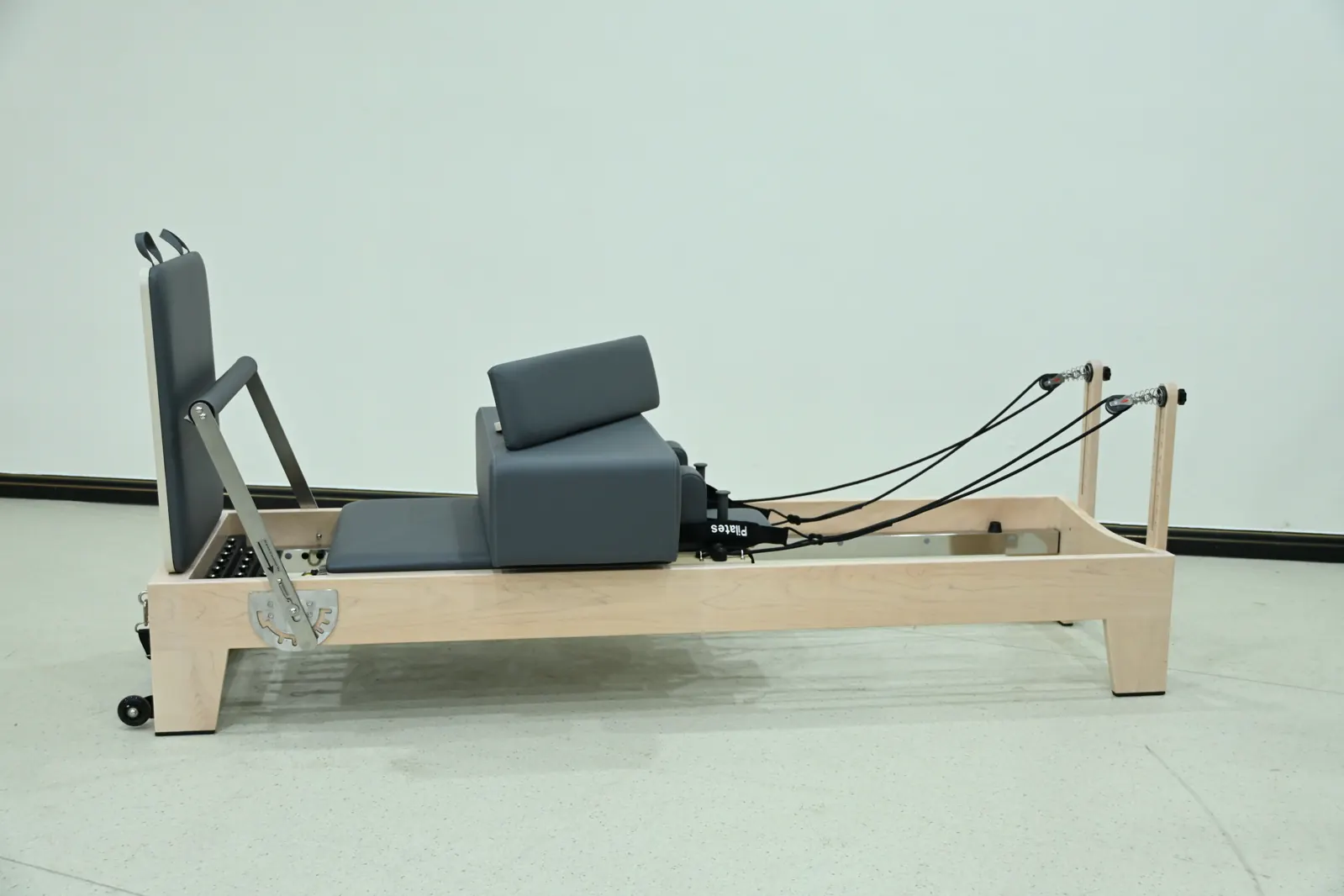 Reformer Pilates con estructura de madera visto de perfil